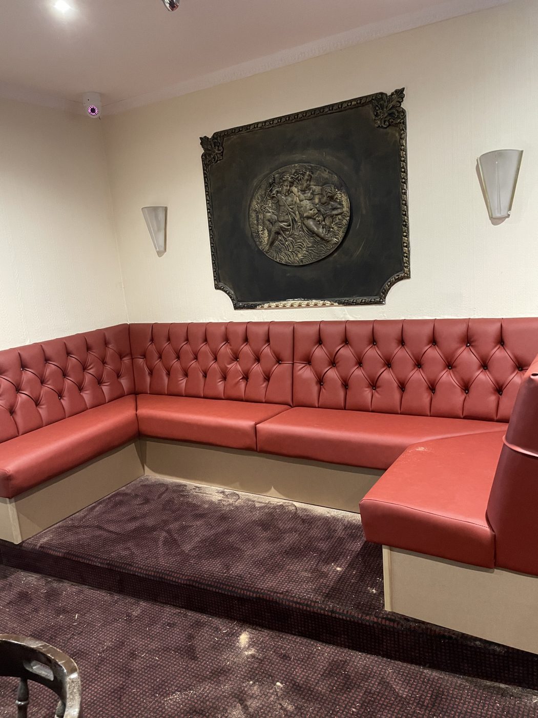 Red deep-buttoned U-shaped banquette seating in a venue